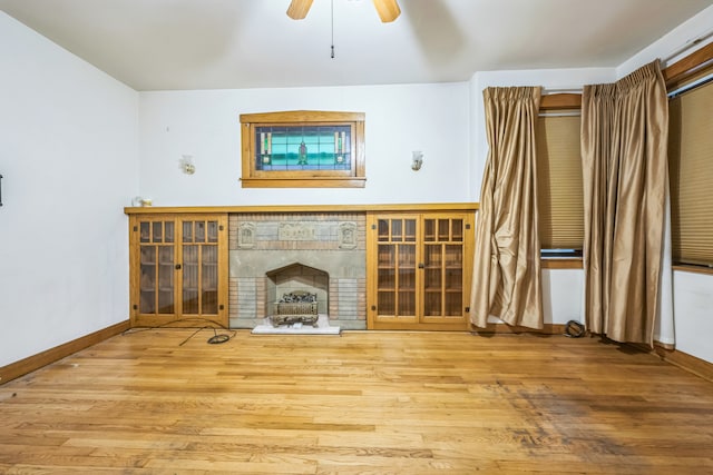 unfurnished living room featuring a brick fireplace, hardwood / wood-style flooring, and ceiling fan