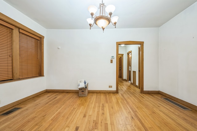 unfurnished room with a chandelier and light wood-type flooring