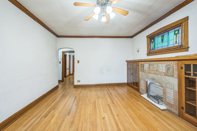 unfurnished living room featuring light hardwood / wood-style floors, crown molding, a fireplace, and ceiling fan