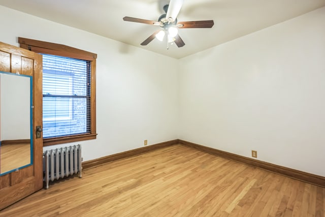 unfurnished room with radiator, light wood-type flooring, and ceiling fan