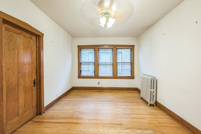 spare room with radiator heating unit, light wood-type flooring, and ceiling fan