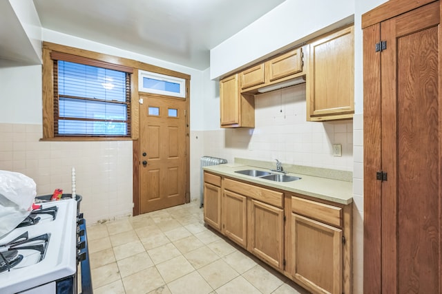 kitchen with tile walls, sink, white stove, and light tile patterned floors