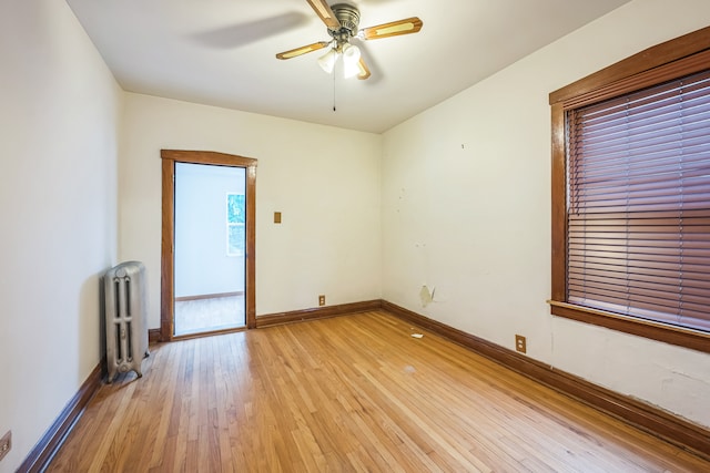 unfurnished room with light hardwood / wood-style flooring, ceiling fan, and radiator