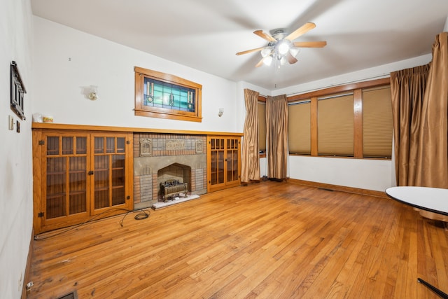 unfurnished living room featuring ceiling fan, hardwood / wood-style flooring, and a brick fireplace