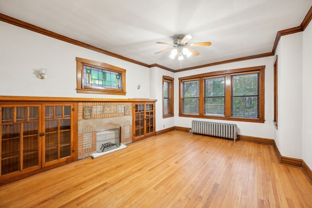 unfurnished living room featuring radiator heating unit, crown molding, light wood-type flooring, a fireplace, and ceiling fan