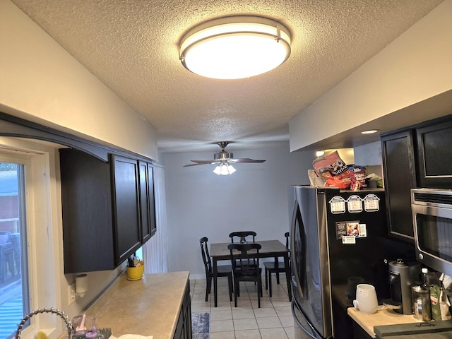 6809 S Joanne Ave, Rochelle, IL 61068 - kitchen featuring a textured ceiling, light tile patterned floors, stainless steel appliances, dark cabinetry, and a ceiling fan