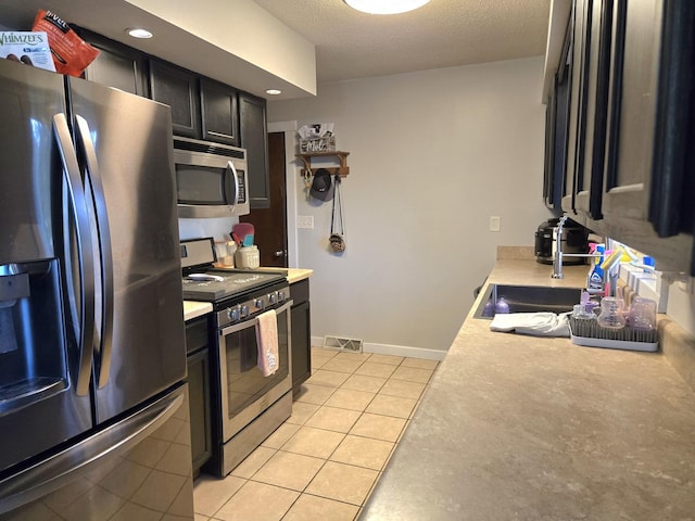 6809 S Joanne Ave, Rochelle, IL 61068 - kitchen featuring stainless steel appliances, light countertops, light tile patterned floors, a textured ceiling, and dark cabinetry