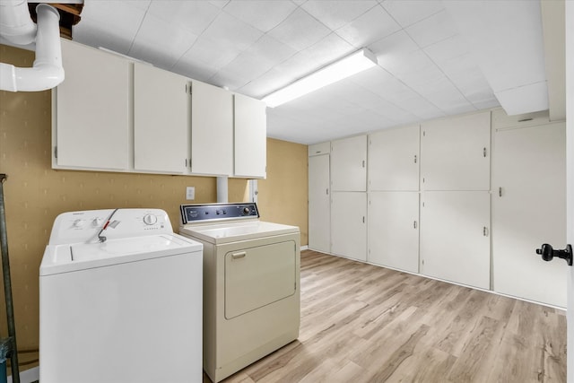 laundry room with cabinets, light wood-type flooring, and separate washer and dryer