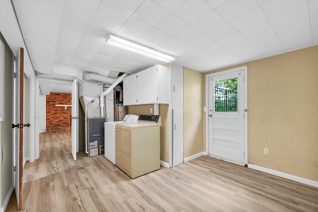 clothes washing area with cabinets, light hardwood / wood-style flooring, and washing machine and dryer