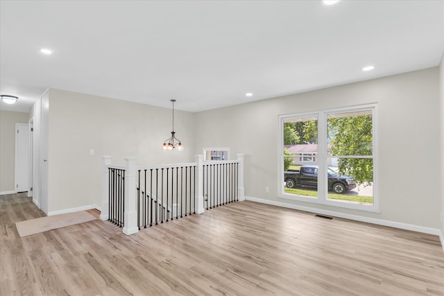 empty room with a chandelier and light hardwood / wood-style floors