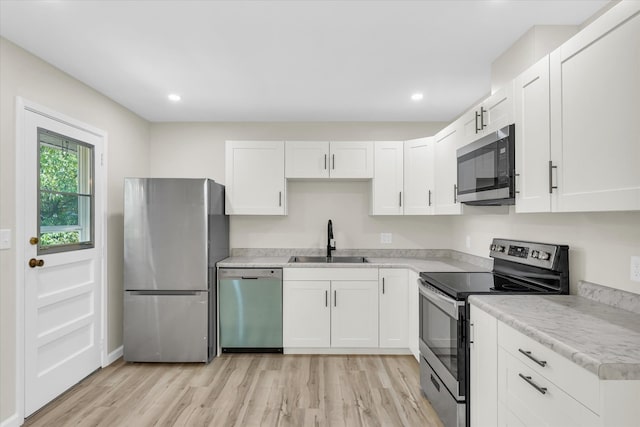 kitchen with light hardwood / wood-style floors, white cabinetry, sink, and stainless steel appliances