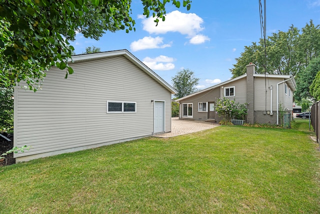 rear view of house with central AC unit and a lawn