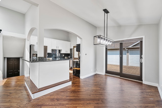 kitchen featuring pendant lighting, dark hardwood / wood-style floors, white cabinets, stainless steel refrigerator with ice dispenser, and decorative backsplash