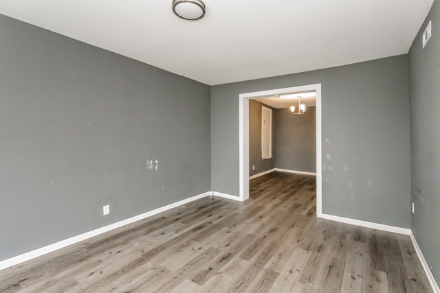 spare room featuring an inviting chandelier and light wood-type flooring