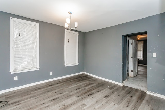 spare room with wood-type flooring and a chandelier