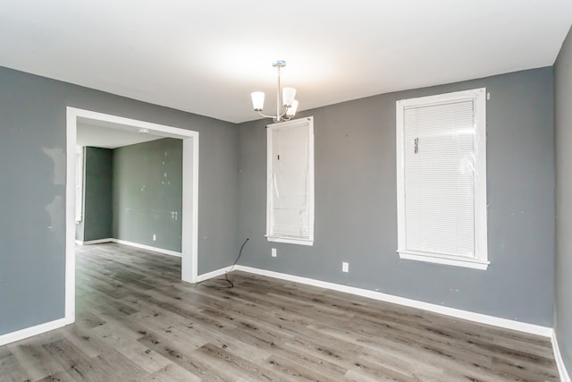 unfurnished room with a notable chandelier and hardwood / wood-style floors