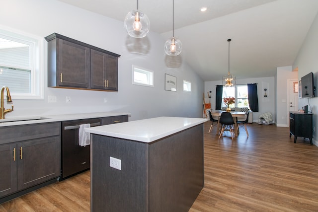 kitchen featuring vaulted ceiling, decorative light fixtures, hardwood / wood-style flooring, stainless steel dishwasher, and sink