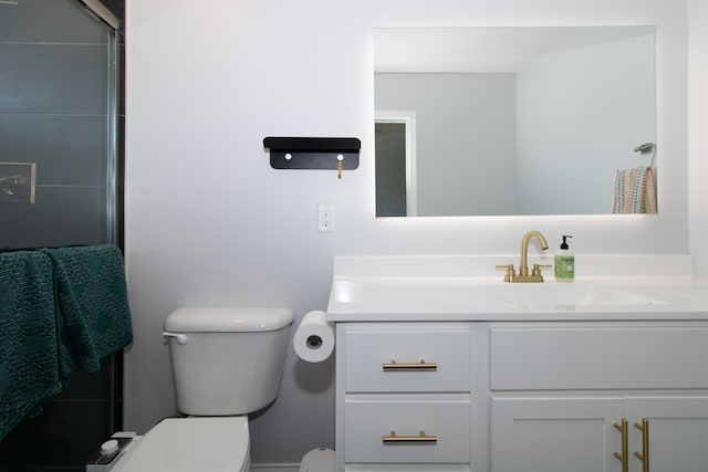 bathroom with vanity, toilet, and a shower with door