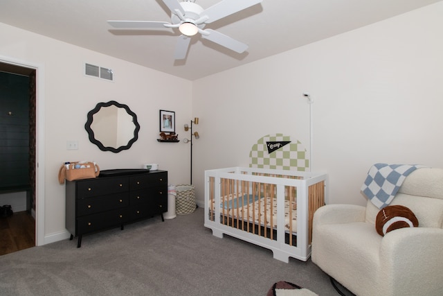 carpeted bedroom featuring ceiling fan and a nursery area