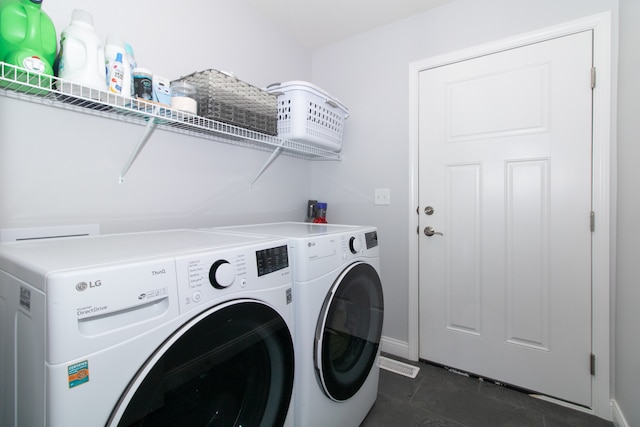 clothes washing area with separate washer and dryer and dark tile patterned flooring