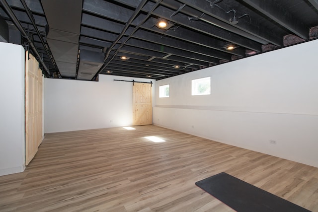 basement with a barn door and hardwood / wood-style flooring