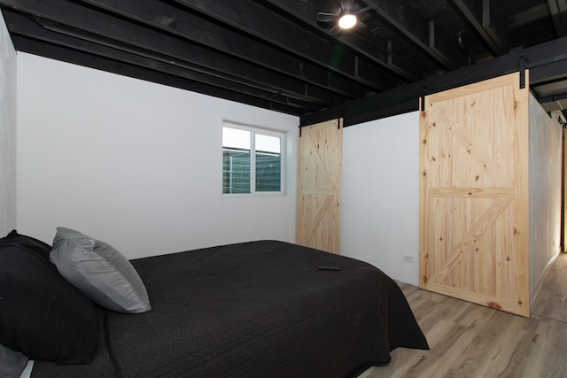 bedroom with a barn door and light hardwood / wood-style flooring