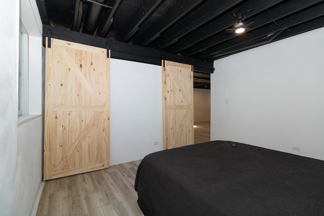 bedroom with light hardwood / wood-style flooring and a barn door