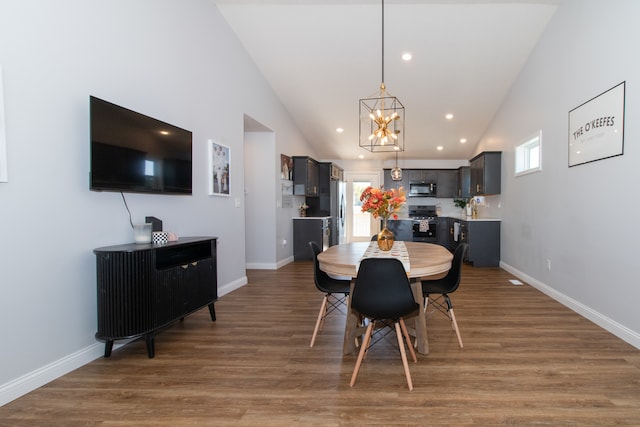 dining room with an inviting chandelier, dark wood-type flooring, and high vaulted ceiling