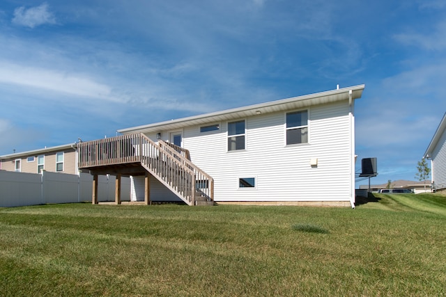 rear view of house with a wooden deck, a lawn, and central AC