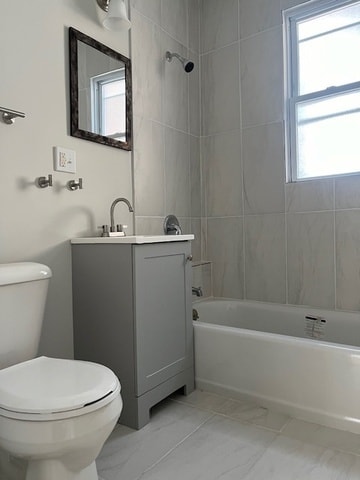 full bathroom featuring tiled shower / bath, vanity, and toilet