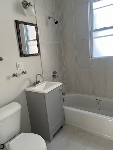 full bathroom with tiled shower / bath combo, vanity, toilet, and a wealth of natural light