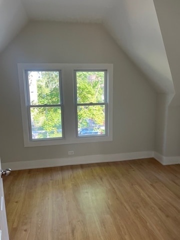 additional living space with light wood-type flooring and vaulted ceiling