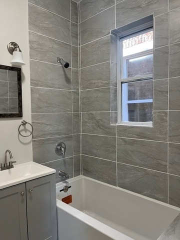 bathroom with tiled shower / bath and vanity