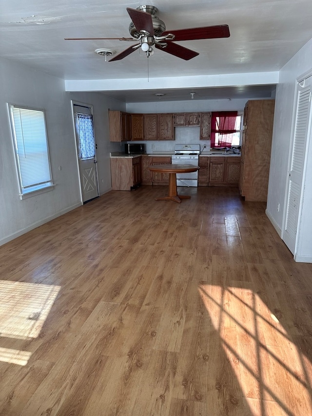 kitchen featuring light hardwood / wood-style flooring, ceiling fan, white gas range, and sink