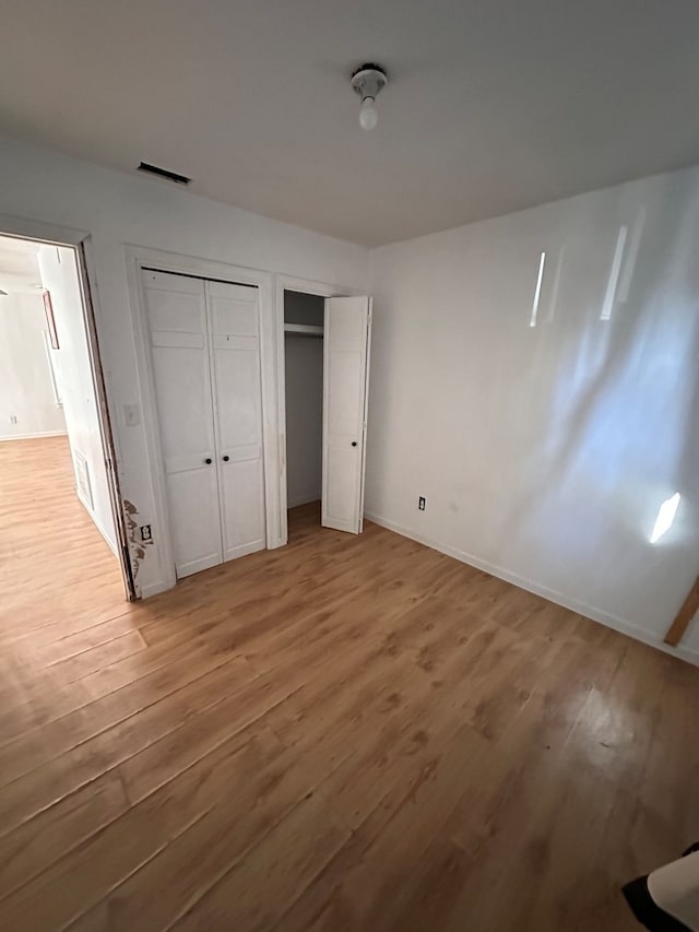 unfurnished bedroom with multiple closets and hardwood / wood-style flooring