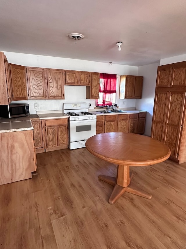 kitchen with sink, hardwood / wood-style floors, and white gas range oven