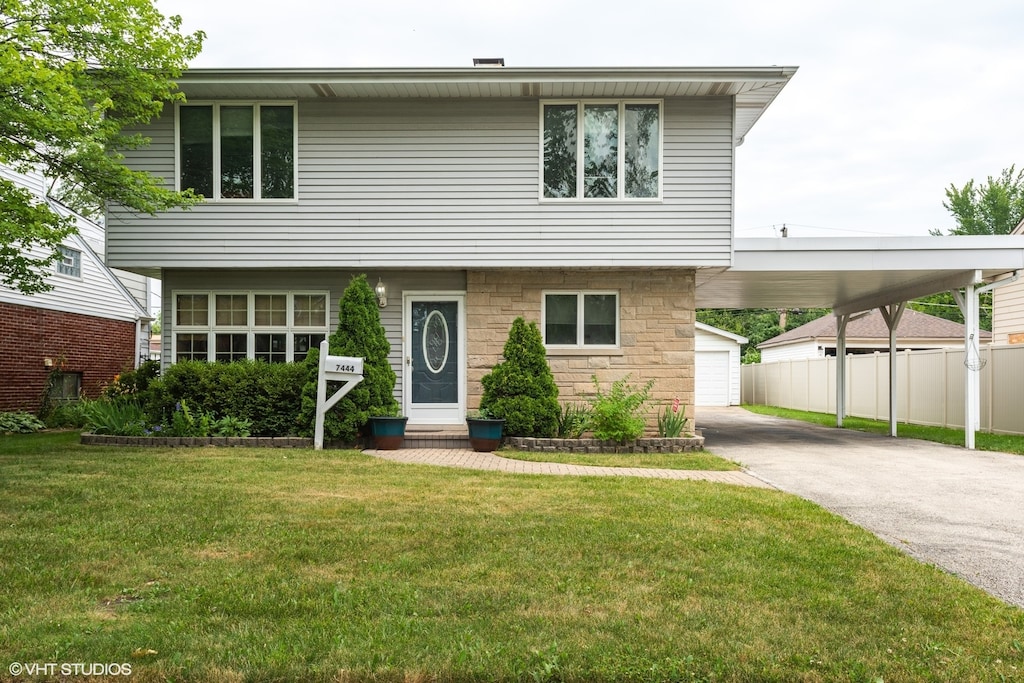 view of front of house with a garage, a front yard, and a carport