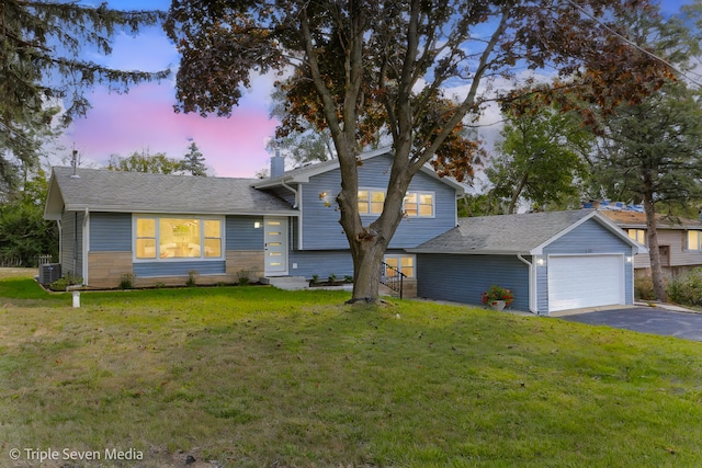 tri-level home with central AC unit, a garage, a yard, and an outbuilding