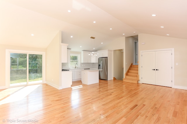 unfurnished living room featuring sink, light hardwood / wood-style floors, and high vaulted ceiling