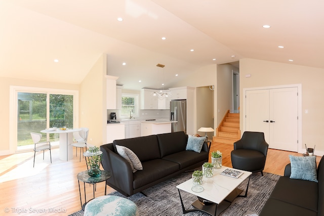 living room with light hardwood / wood-style floors, lofted ceiling, and sink