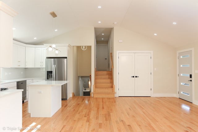 kitchen with a center island, white cabinets, vaulted ceiling, light hardwood / wood-style flooring, and stainless steel fridge