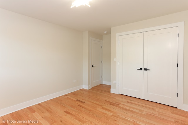 unfurnished bedroom with light wood-type flooring and a closet