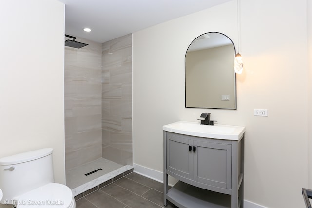 bathroom featuring vanity, tile patterned floors, toilet, and tiled shower