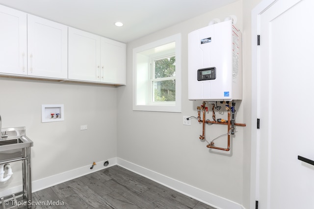 clothes washing area featuring hookup for a washing machine, tankless water heater, cabinets, gas dryer hookup, and dark hardwood / wood-style floors