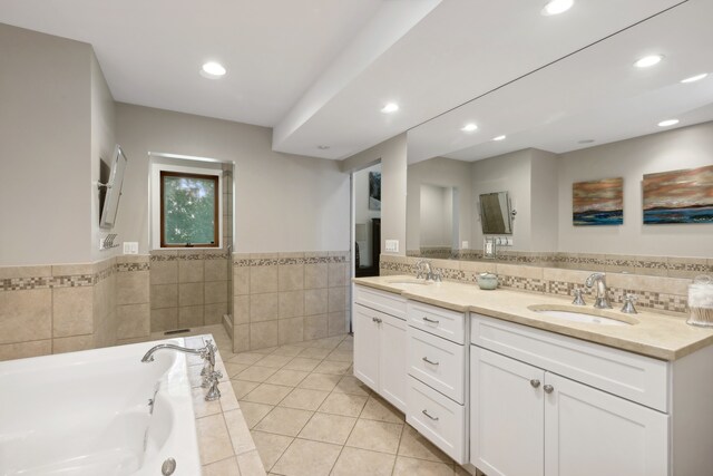 bathroom with vanity, a relaxing tiled tub, and tile patterned floors