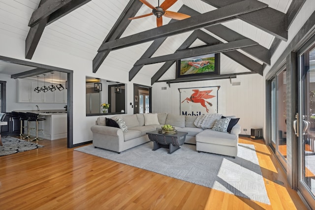 living room featuring light hardwood / wood-style floors, beam ceiling, ceiling fan, and high vaulted ceiling