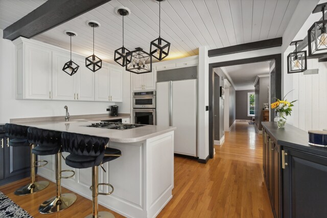 kitchen with white cabinetry, light hardwood / wood-style floors, appliances with stainless steel finishes, and hanging light fixtures