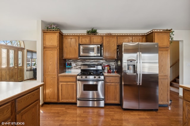 kitchen featuring stainless steel appliances, backsplash, and dark hardwood / wood-style flooring