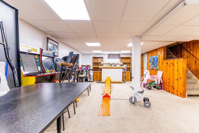 game room featuring a drop ceiling, wood walls, and carpet flooring