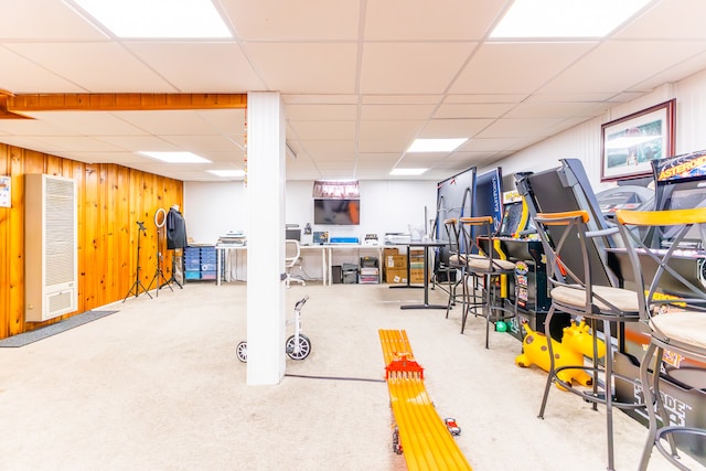 interior space featuring carpet floors, wooden walls, and a drop ceiling